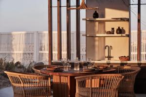 a table with chairs and wine glasses on a patio at Casa Cook North Coast - Adults Only in El Alamein