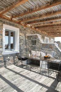 eine Terrasse mit einem Tisch, Stühlen und einer Steinmauer in der Unterkunft Africanis Bungalows in Schinoussa