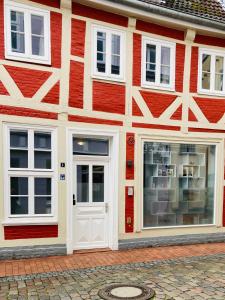 a red and white building with a white door at Das Stader Wohnzimmer in Stade
