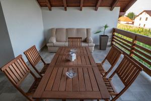 eine Terrasse mit einem Holztisch, Stühlen und einem Sofa in der Unterkunft Pensiunea Gassi in Sancraiu de Mures