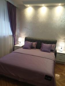 a bedroom with a large bed with purple pillows at Elena Lux in Belgrade