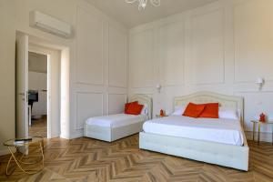 2 bedden met oranje kussens in een witte kamer bij agropoli luxury home in Agropoli