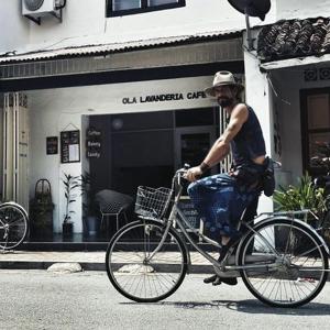 un homme faisant du vélo devant un magasin dans l'établissement Ola Hostel, à Malacca
