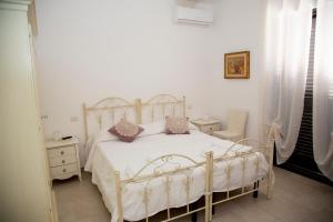 um quarto com uma cama branca com almofadas cor-de-rosa em La casetta nel bosco em Castellana Grotte