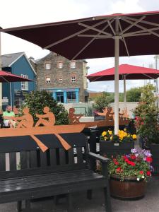 a bench with an umbrella and some plants and flowers at Riverview Apartment in Skibbereen