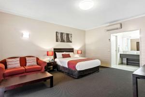 a hotel room with a bed and a couch and a sink at Quality Inn Colonial in Bendigo