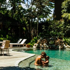 a man and a child in a swimming pool at Pousada Capim Santo in Trancoso