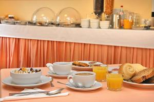 Hotel Marina في باردولينو: طاولة مليئة بالأكواب وأطباق طعام الإفطار