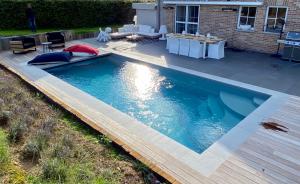a large swimming pool with a deck and a patio at BB La Marinière in Theux