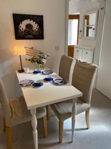 biały stół jadalny z 2 krzesłami i kwiatami na nim w obiekcie Ferienwohnung Nele w mieście Waldesch