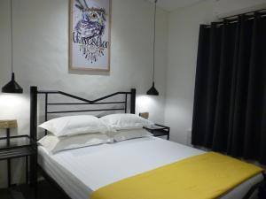 a bedroom with a large white bed with a yellow blanket at Ola Hostel in Melaka