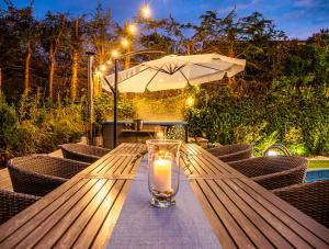 a candle on a wooden table with chairs and an umbrella at Domek InoSasino z basenem i sauną in Sasino