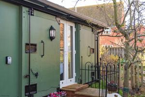 a green house with a white door and a porch at Plumcot Halt by Bloom Stays in Canterbury