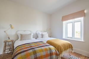 zwei Betten in einem weißen Zimmer mit Fenster in der Unterkunft East Cottage by Bloom Stays in Dungeness