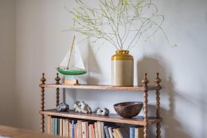 ein Regal mit Büchern und eine Vase mit einem Boot drauf in der Unterkunft East Cottage by Bloom Stays in Dungeness