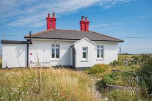 ein weißes Haus mit zwei Schornsteinen auf einem Feld in der Unterkunft East Cottage by Bloom Stays in Dungeness