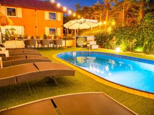 a swimming pool with chairs and an umbrella next to a house at Domek InoSasino z basenem i sauną in Sasino