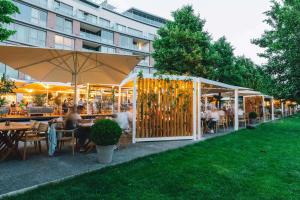 Eurovea Apartments في براتيسلافا: مطعم فيه ناس جالسين على الطاولات في الحديقة
