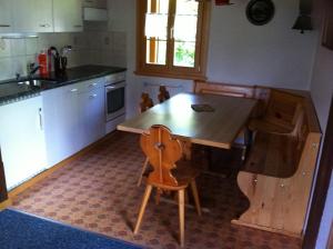 a kitchen with a wooden table and a wooden chair at Chalet Erika in Eriz