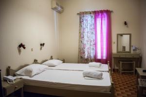a bedroom with two beds and a window with pink curtains at Argostoli Hotel in Argostoli