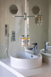 La salle de bains est pourvue d'un lavabo blanc et de deux miroirs. dans l'établissement Hotel Mondego, à Coimbra