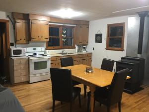 a kitchen with a wooden table with chairs and a stove at Riverfront Rustic Cottage in Durham Bridge