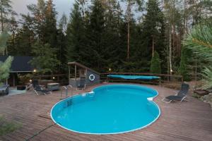 a pool on a deck with chairs and a table at Sirpa's Artistic Nuuksio Retreat with Heated Pool in Espoo