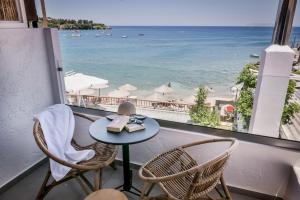 einen Tisch und Stühle auf einem Balkon mit Blick auf den Strand in der Unterkunft Laia Seafront Luxury Apartments in Agia Pelagia