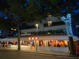 LA MAISON by Hotel Aldebaran في ليدو دي يسولو: مجموعة من الناس يجلسون خارج المبنى في الليل