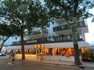 um prédio com um restaurante com pessoas andando na frente dele em LA MAISON by Hotel Aldebaran em Lido di Jesolo