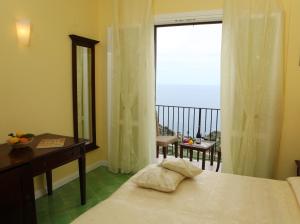 a bedroom with a bed and a desk and a window at Torre Bennistra in Scopello