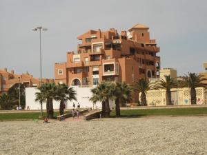 un grand bâtiment avec des palmiers devant lui dans l'établissement Apartamento en primera línea de playa, con vistas a la playa y con wifi, à Roquetas de Mar