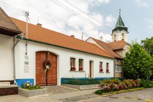 un edificio blanco con una torre del reloj y una iglesia en U Stařenky en Dolní Bojanovice