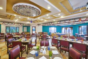 un restaurante con mesas y sillas y una gran lámpara de araña en Club Mahindra Kumbhalgarh, en Kumbhalgarh