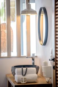 ein Bad mit einem Waschbecken und einem Spiegel in der Unterkunft Laia Seafront Luxury Apartments in Agia Pelagia