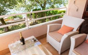 a balcony with a chair and a table with a bottle of wine at Apartman Neda -Vantacici Malinska in Vantačići