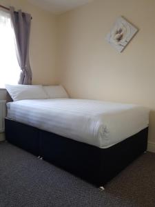 1 dormitorio con 1 cama con sábanas blancas y ventana en Bella Room with free minibar tea&coffee en Dublín