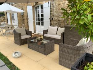 een patio met rieten stoelen en een tafel bij Amity. Exclusive poolside garden apartment in Sarlat-la-Canéda