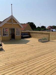 a large wooden deck in front of a house at luksus spahus i skagen in Skagen