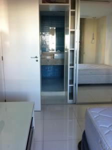 1 dormitorio con 1 cama y puerta al baño en Best Barra Beach Apartment en Río de Janeiro