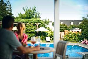 a man and woman sitting at a table near a pool at Inn at Perry Cabin in Saint Michaels