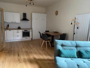 a living room with a blue couch and a kitchen at Apartmán Anna Viktoria v Brčálníku in Frischwinkel