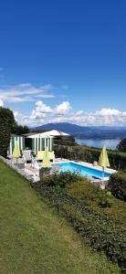 una piscina con sillas y sombrillas junto a una casa en Villa Marisa en Nebbiuno
