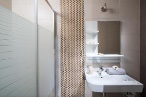 een badkamer met een wastafel en een douche met een spiegel bij Coast Suite-Luxury Central Beach House in Chersonissos