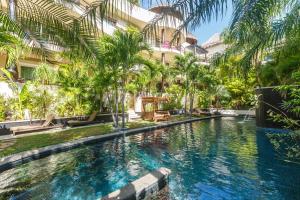 a swimming pool in front of a building with palm trees at El Taj Oceanfront and Beachside Condo Hotel in Playa del Carmen