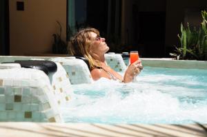 a woman sitting in a swimming pool holding a drink at El Taj Oceanfront and Beachside Condo Hotel in Playa del Carmen