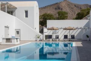 ein Pool mit einem weißen Haus und Bergen im Hintergrund in der Unterkunft Petra Aqua Villa in Perissa