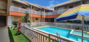 - une piscine avec un parasol à côté d'un bâtiment dans l'établissement Pousada Peruíbe Ametista, à Peruíbe