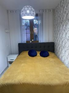 a bedroom with a large yellow bed with blue pillows at Nowoczesny Apartament Nad Łomnicą in Karpacz