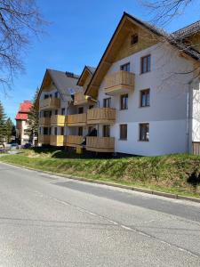 a white building with wooden balconies on the side of a road at Nowoczesny Apartament Nad Łomnicą in Karpacz